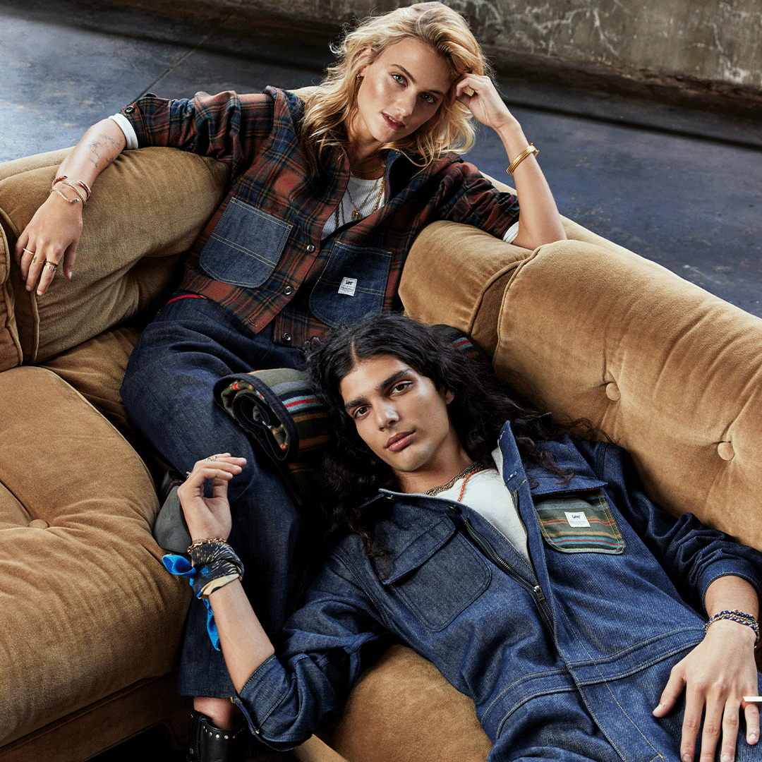 Two models wearing clothing from the Lee/Pendleton collaboration lounge on a sofa.